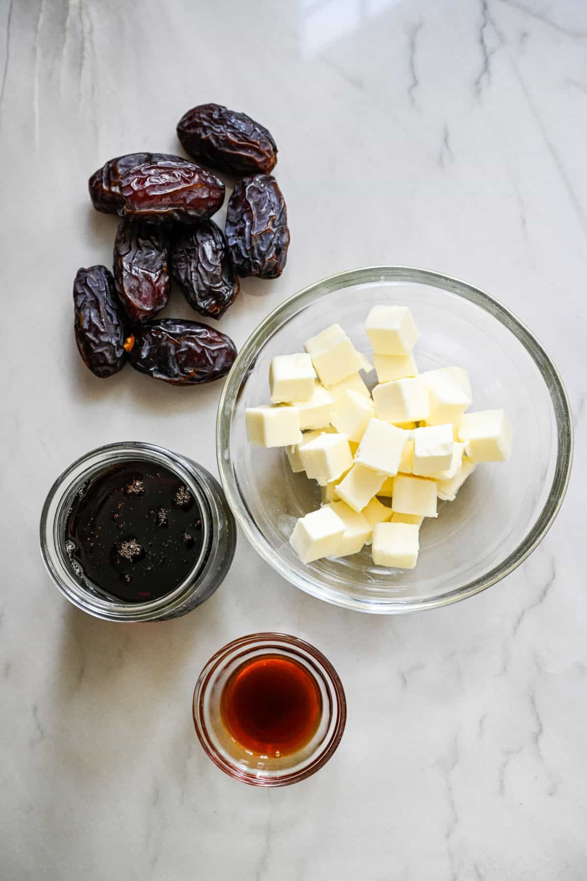 overhead view of butter, dates, maple syrup and vanilla extract to show ingredients for date caramel sauce.