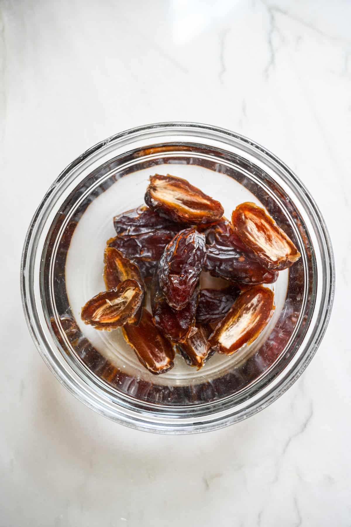 Dates cut in half soaking in a bowl of water.