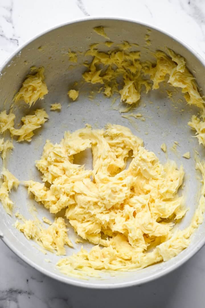 Pale, fluffy creamed butter mixture in a large speckled mixing bowl.