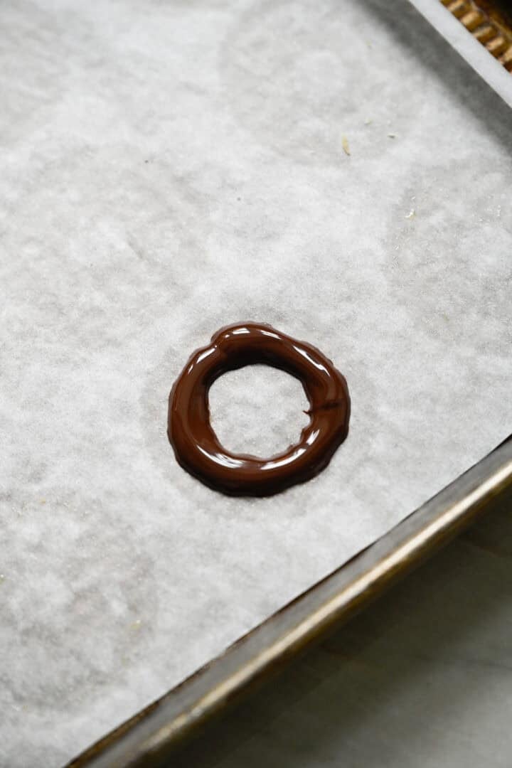 Ring of melted dark chocolate piped onto a parchment-lined baking sheet.