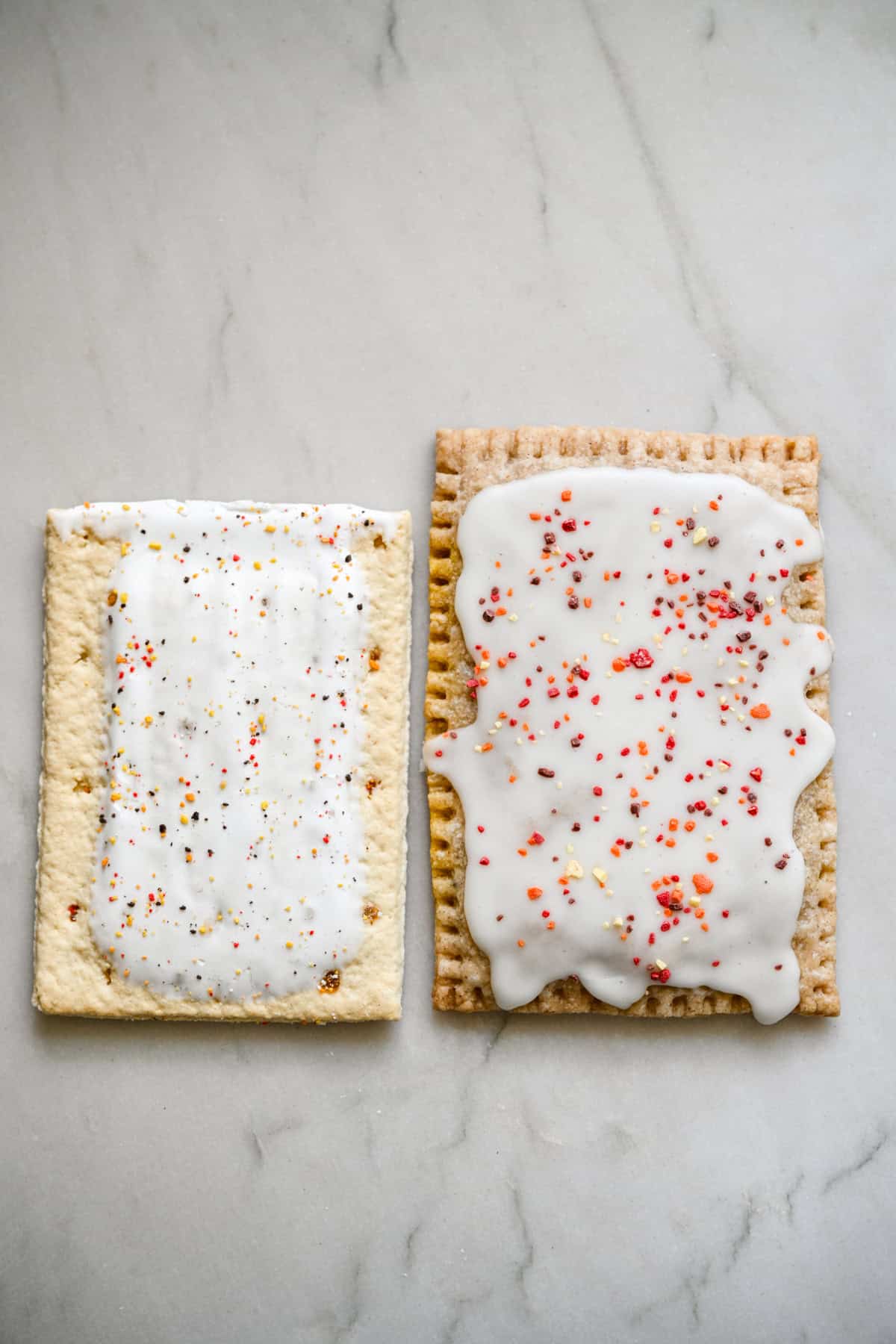 A store-bought pumpkin pie pop tart next to a homemade one on a marble countertop.