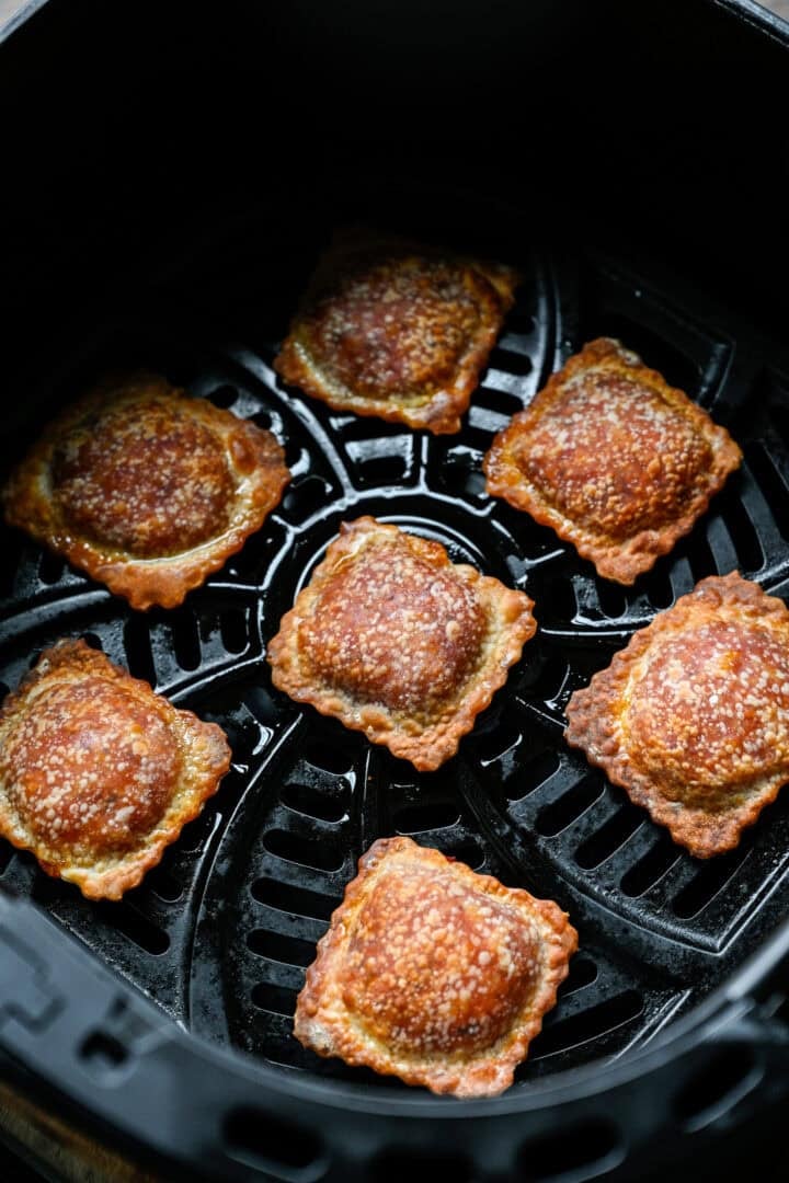 Golden brown, crispy pizza rolls in an air fryer basket after cooking.
