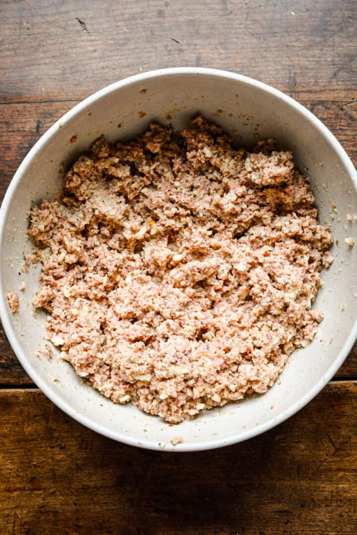 Overhead view of the sausage filling mixed together in a white bowl.
