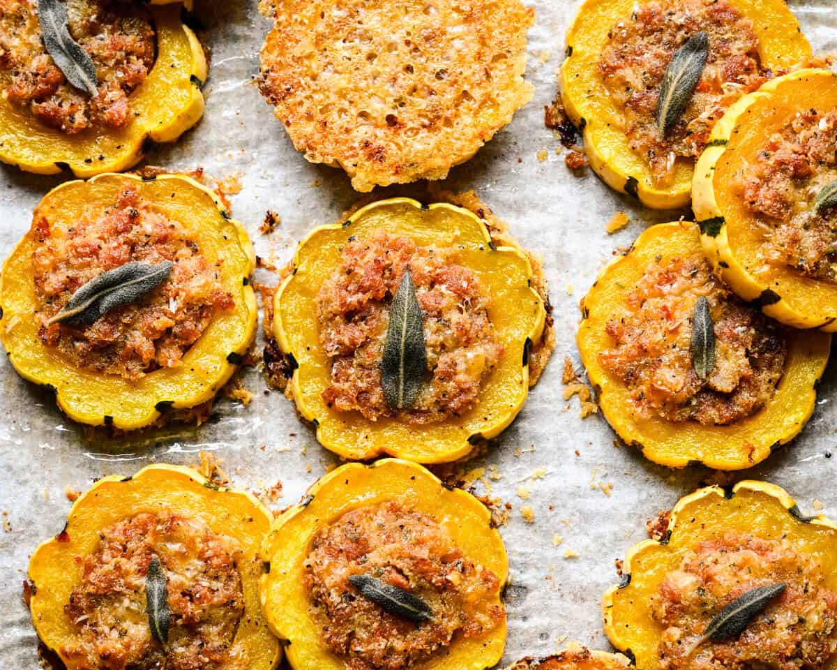 Close up view of stuffed delicata squash rings and a parmesan crisp on parchment.