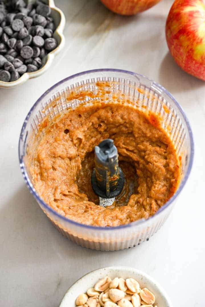 45 degree view of dates blended into a thick paste in a small food processor.